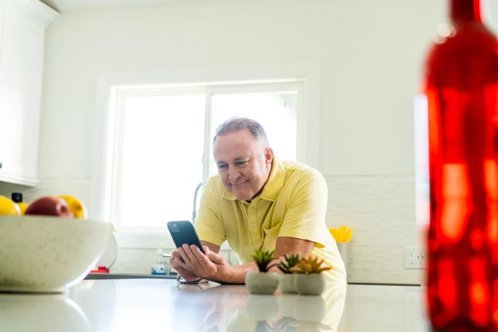 An older man smiling on his phone while he books a free estimate with One Hour Heating and Air Conditioning- Phoenix West Valley.