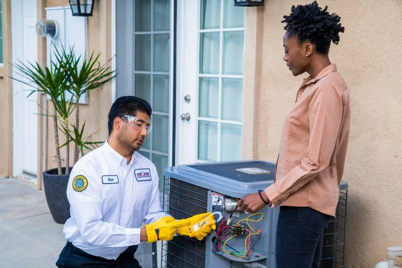 A One Hour Heating and Air Conditioning- Phoenix West Valley tech and a customer discussing diagnostic issues with an outdoor residential unit in Sun City, AZ.