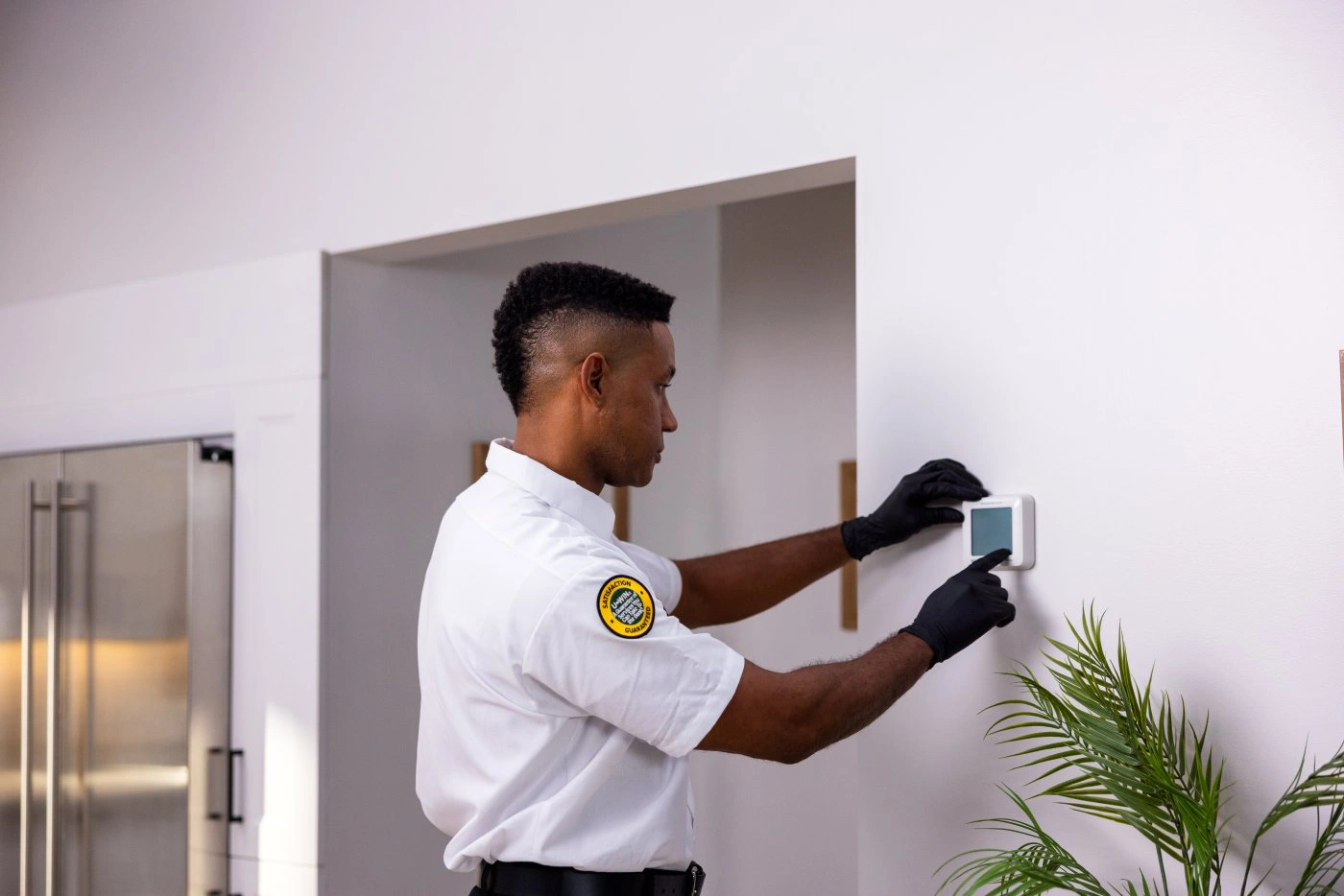 One Hour Heating and Air Conditioning tech checking an indoor thermostat for a Phoenix West Valley homeowner.