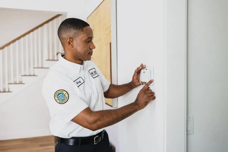 A One Hour Heating and Air Conditioning tech assessing an indoor thermostat after a routine AC maintenance in Surprise, AZ