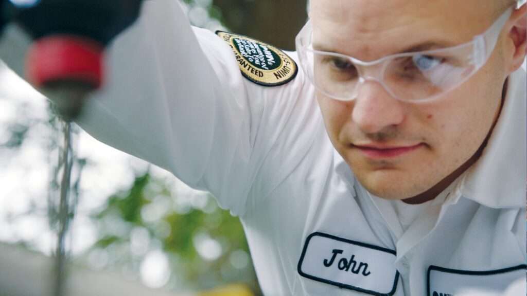 A close-up of One Hour Heating and Air Conditioning-Phoenix West Valley tech, John, with safety glasses on checking an outdoor HVAC unit in Sun City West, AZ.
