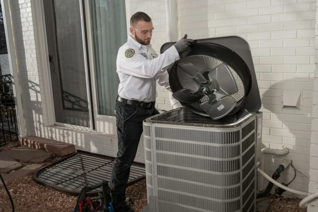 One Hour Heating and Air Conditioning working on AC Repairs by lifting the fan and checking inside the outdoor AC unit in the Phoenix West Valley.